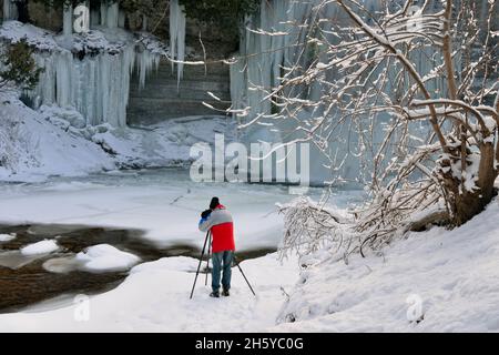 Fotografo sotto Bridal Veil Falls e il fiume Kagawong in inverno, Kagawong, Manitoulin Island, Ontario, Canada Foto Stock