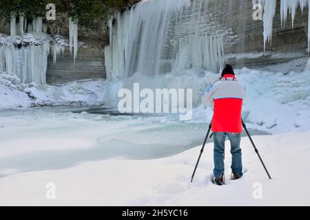 Fotografo sotto Bridal Veil Falls e il fiume Kagawong in inverno, Kagawong, Manitoulin Island, Ontario, Canada Foto Stock