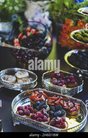 Colpo verticale di un tavolo con vari tipi di dessert con frutta diversa Foto Stock