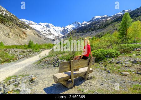 Donna con maglietta rossa sul sentiero escursionistico fino al ghiacciaio Morteratsch della Svizzera. Il più grande ghiacciaio della catena Bernina delle Alpi Bundner dei Grigioni Foto Stock