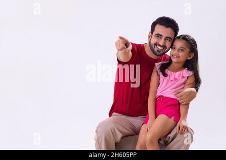 UN PADRE CHE PUNTA FELICEMENTE VIA MENTRE LA FIGLIA SEDUTA SUL GIRO Foto Stock