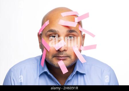 Ritratto di un calvo con note appiccicose sul viso su sfondo semplice. Foto Stock