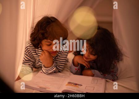 Fratello che studia insieme il libro sul letto con attenzione Foto Stock