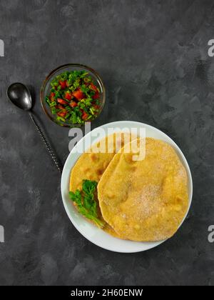 Pane piatto di mais fatto in casa con salsa di pomodoro al coriandolo. Tortilla messicana artigianale insalata di verdure tradizionale indiana Foto Stock