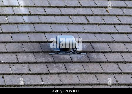 Un ritratto di una bocca sul tetto di una casa in ardesia. Questo piccolo camino come oggetto è usato come ventilazione, per ventilare una casa e regolare la A. Foto Stock