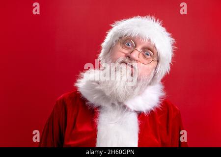 Pazzo Babbo Natale faccia divertente isolato su sfondo rosso studio. Adempimento dei desideri. Foto Stock