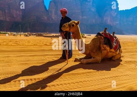 Wadi Rum, Giordania - 22 ottobre 2021: Un giovane beduino, con il suo cammello, nel paesaggio di Wadi Rum, parco desertico nel sud della Giordania Foto Stock