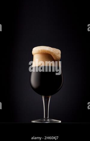 Bicchiere di birra scura su sfondo nero. Foto Stock