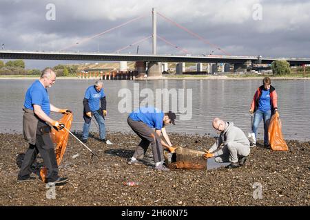 Dotati di pinze e sacchetti riciclabili per rifiuti, volontari dell'organizzazione ambientale KRAKE e.V. raccogliere rifiuti sulla riva sinistra del Reno di fronte al ponte Leverkusen vicino a Colonia, 26 ottobre 2021 -- - ausgestattet mit Greifzangen und recycelbaren Müllsäcken sammeln Freiwillige der Umweltorganisation KRAKE e.V. das linksrheinische Ufer vor der Leverkusener Brücke bei Köln Unrat und Müll. Köln, 26.10.2021 Foto Stock