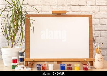 Carta bianca bianca bianca per la pittura su cavalletto di legno sul tavolo dello studio di casa Foto Stock