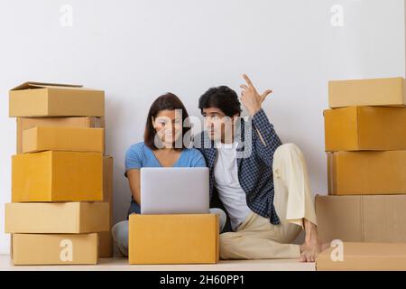 La coppia indiana di mezza età guarda insieme il computer portatile disimballato dopo essere stato spostato nella nuova stanza Foto Stock