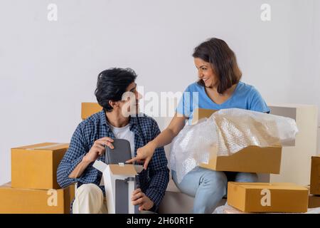 La coppia indiana di mezza età si guarda l'un l'altro durante il disimballaggio delle scatole di cartone nella stanza nuova Foto Stock