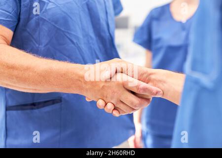 I medici nella sala operatoria scuotono le mani prima dell'operazione come simbolo di cooperazione e successo Foto Stock
