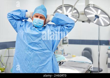 Estenuante chirurgo che si allunga nel pronto soccorso dopo un'operazione faticosa Foto Stock