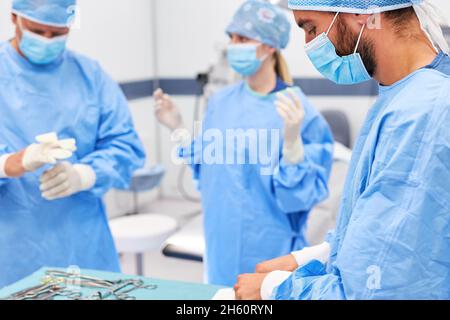 Ambulatorio medico squadra in indumenti protettivi sterili preparazione per un intervento Foto Stock