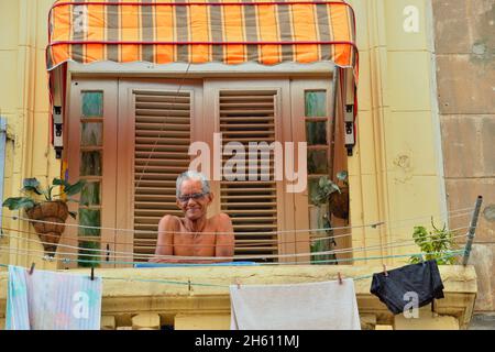Un uomo seduto su un balcone che si affaccia su Calle Neptuno a l'Avana Centrale, la Habana (l'Avana), Habana, Cuba Foto Stock