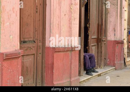 Scena stradale nel centro di l'Avana. Dettagli architettonici coloniali - porta aperta con uomo seduto, la Habana (l'Avana), Habana, Cuba Foto Stock