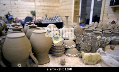 Un sacco di ceramiche fatte in casa. Riprese in stock. Terracotta grigia con molti vasi e piastre identici sul tavolo in officina. Laboratorio di ceramica. Foto Stock