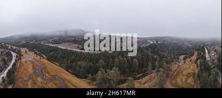 Veduta aerea panoramica del sobborgo Vodice in autunno nebbia mattina, paesaggio con fiume, pini e pascoli sul monte Zlatibor, Serbia. Foto Stock