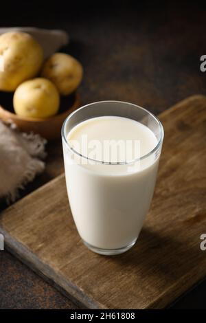 Latte di patate su sfondo marrone. Formato verticale. Primo piano. Prodotto di sostituzione del latte a base di piante e privo di lattosio. vega alternativa privo di colesterolo e grassi Foto Stock