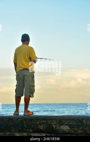 Malecón (ufficialmente Avenida de Maceo) ha fatto da sagome ai pescatori che si trovavano in piedi sul muro di mare la mattina . La Habana (l'Avana), Habana, Cuba Foto Stock