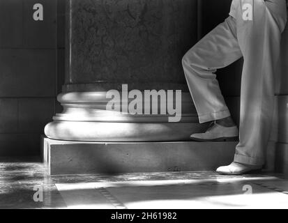 Gambe e piedi di un uomo ben vestito in piedi da una colonna al Campidoglio dello Stato del Nebraska, Lincoln, Nebraska; 1934 Foto Stock