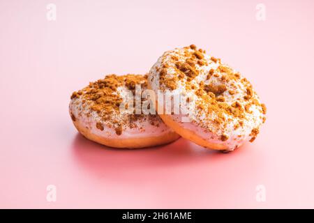 Ciambella glassata dolce con spolverini su sfondo rosa. Foto Stock