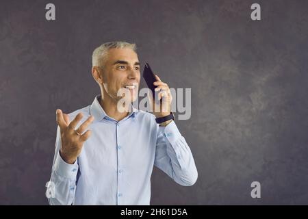 Conversazione uomo di mezza età riuscita durante una chiamata con lo smartphone Foto Stock