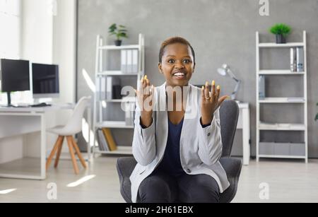 Divertente e allegro manager aziendale femminile seduto di fronte alla webcam e comunicando tramite videochiamata. Foto Stock