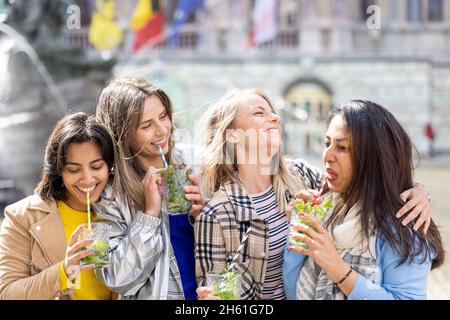 Gruppo etnico Muti di amici femminili che si divertono bevendo cocktail all'aperto in città nel bar ristorante. Foto di alta qualità Foto Stock