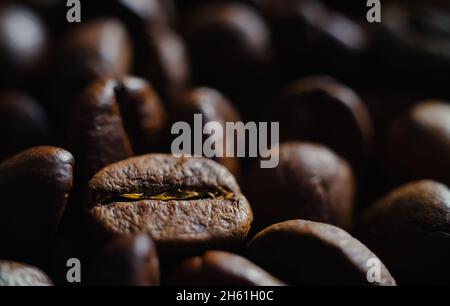 Chicchi di caffè tostati scuri in primo piano. Ingredienti freschi e aromatici per l'espresso Foto Stock