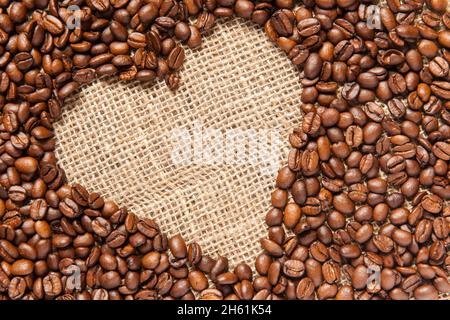 Vista formatabile di una struttura inclinata a forma di cuore realizzata con chicchi di caffè torrefatti su sackcount. Foto Stock