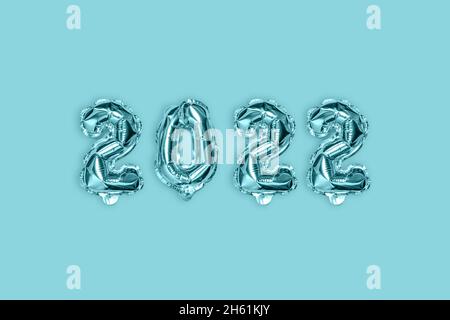 2022 decorazione blu argento vacanza su sfondo blu. Palloncini in lamina d'oro numero. Disposizione piatta, vista dall'alto. Foto Stock