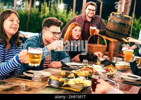Gli uomini e le donne felici che hanno bevuto la birra alla festa del giardino del patio - concetto sociale di stile di vita di riunione sui giovani amici che godono del tempo di hangout Foto Stock