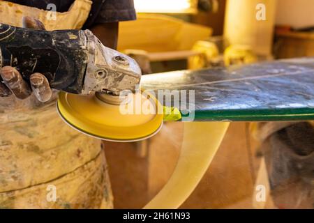 Primo piano di un artigiano africano tavola da surf Shaper lavorare in un'officina di riparazione Foto Stock