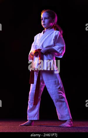 Ritratto a tutta lunghezza di karate sportivo piccolo gir training isolato su sfondo bianco. Concetto di sport, educazione, abilità Foto Stock