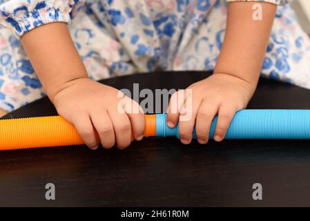 Fidget Pop tubi sensoriali giocattolo. Cute bambino senza volto giocando con il Pop tubi Fidget. Foto Stock