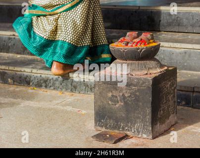 Donna indiana in tradizionale saree camminando al piano superiore passando per la statua dei piedi all'ingresso del Tempio di Ganesh in Gokulam, Mysore, India Foto Stock