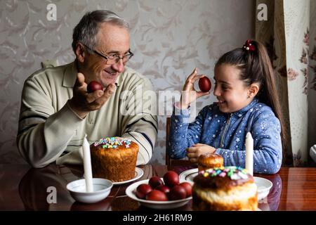 Famiglia decorazione uova di Pasqua su tavola, nonno e nipote. Foto Stock