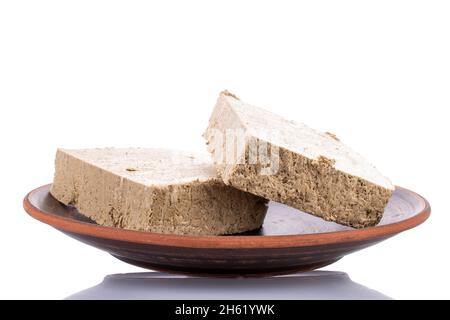 Due fette di alva alla vaniglia su un piatto di argilla, primo piano, isolato su bianco. Foto Stock