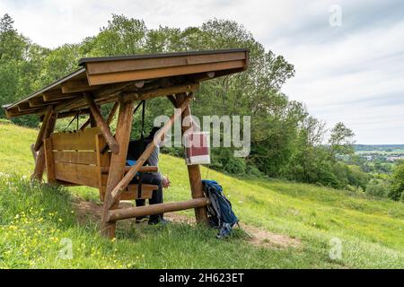 europa,germania,baden-wuerttemberg,regione di schönbuch,waldenbuch,escursionista siede su un'altalena di legno nel knaupwiesen e guarda a waldenbuch Foto Stock