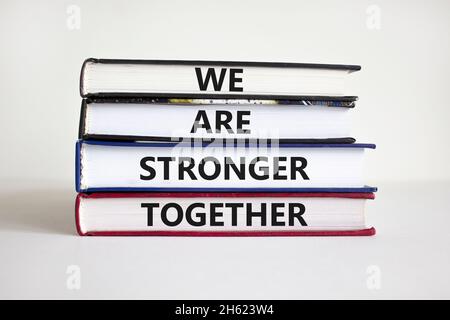 Simbolo più forte insieme. Libri con le parole "noi siamo più forti insieme". Bellissimo sfondo bianco. Mano dell'uomo d'affari. Spazio di copia. Business, motivazione Foto Stock