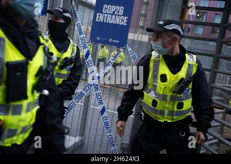 Glasgow, Scozia, Regno Unito. I poliziotti si schierano accanto al nastro che recita “Climate Crime Scene”, legato alla recinzione dei manifestanti climatici, al recinto di sicurezza fuori della sede della Conferenza delle Nazioni Unite sul cambiamento climatico COP26, mentre la conferenza e le riunioni si concludono all’interno di Glasgow, Scozia, il 12 novembre 2021. Foto: Jeremy Sutton-Hibbert/ Alamy Live News. Foto Stock