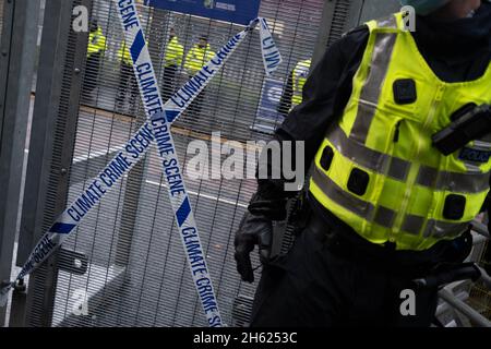 Glasgow, Scozia, Regno Unito. I poliziotti si schierano accanto al nastro che recita “Climate Crime Scene”, legato alla recinzione dei manifestanti climatici, al recinto di sicurezza fuori della sede della Conferenza delle Nazioni Unite sul cambiamento climatico COP26, mentre la conferenza e le riunioni si concludono all’interno di Glasgow, Scozia, il 12 novembre 2021. Foto: Jeremy Sutton-Hibbert/ Alamy Live News. Foto Stock