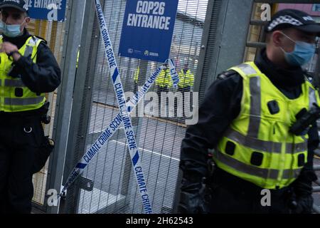 Glasgow, Scozia, Regno Unito. I poliziotti si schierano accanto al nastro che recita “Climate Crime Scene”, legato alla recinzione dei manifestanti climatici, al recinto di sicurezza fuori della sede della Conferenza delle Nazioni Unite sul cambiamento climatico COP26, mentre la conferenza e le riunioni si concludono all’interno di Glasgow, Scozia, il 12 novembre 2021. Foto: Jeremy Sutton-Hibbert/ Alamy Live News. Foto Stock