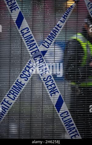 Glasgow, Scozia, Regno Unito. I poliziotti si schierano accanto al nastro che recita “Climate Crime Scene”, legato alla recinzione dei manifestanti climatici, al recinto di sicurezza fuori della sede della Conferenza delle Nazioni Unite sul cambiamento climatico COP26, mentre la conferenza e le riunioni si concludono all’interno di Glasgow, Scozia, il 12 novembre 2021. Foto: Jeremy Sutton-Hibbert/ Alamy Live News. Foto Stock