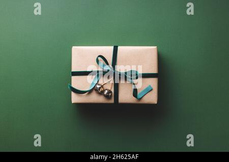 Scatola regalo di Natale legato nastro di velluto su sfondo verde. Foto Stock