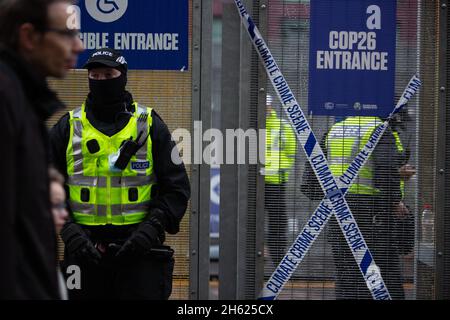 Glasgow, Scozia, Regno Unito. I poliziotti si schierano accanto al nastro che recita “Climate Crime Scene”, legato alla recinzione dei manifestanti climatici, al recinto di sicurezza fuori della sede della Conferenza delle Nazioni Unite sul cambiamento climatico COP26, mentre la conferenza e le riunioni si concludono all’interno di Glasgow, Scozia, il 12 novembre 2021. Foto: Jeremy Sutton-Hibbert/ Alamy Live News. Foto Stock