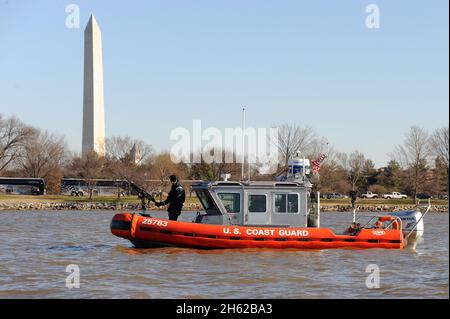 Reportage: A U.S. Coast Guard Petty Officer 2a classe mans una mitragliatrice montata su una barca di risposta di 25 piedi-Small di fronte al monumento di Washington a Washington, 19 gennaio 2013. Foto Stock