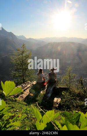 due giovani donne celebrano, gioiscono in controluce, sullo sfondo il kranzberg, wettersteingebirge estergebirge al tramonto, fotografato alla capanna del mittenwalder sul karwendel, mittenwald, alta baviera, valle isar, baviera, germania, europa Foto Stock